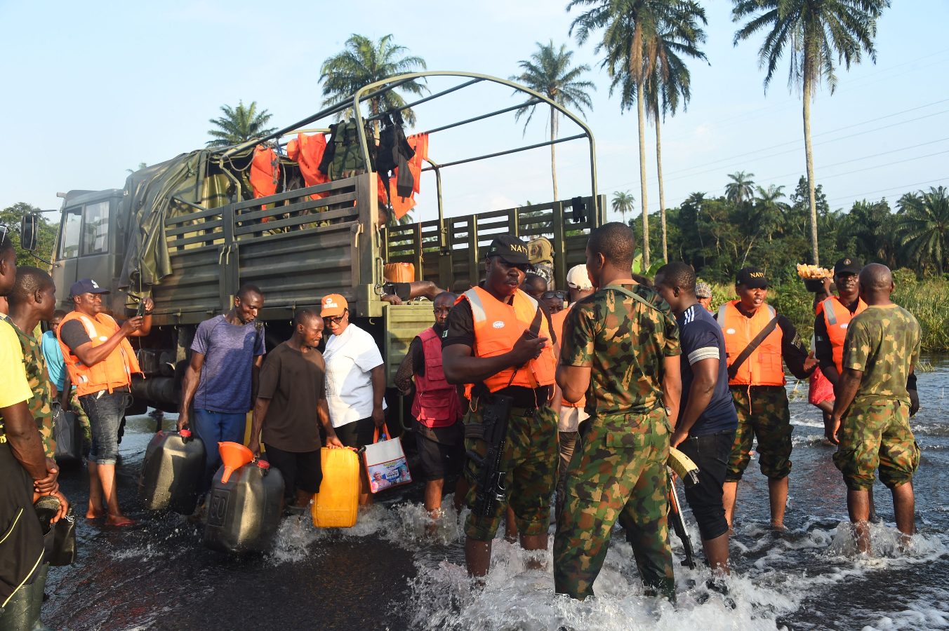 A group of Nigerians standing in flooded waters carry supplies onto a military truck after devastating flooding in September 2022.