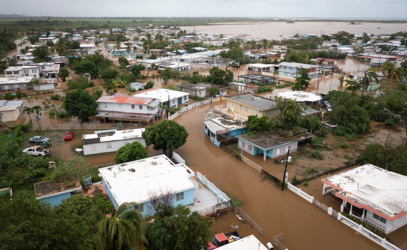 An aerial view of a street with many small homes flooded with brown water after a hurricane in Salinas, Puerto Rico, 2022