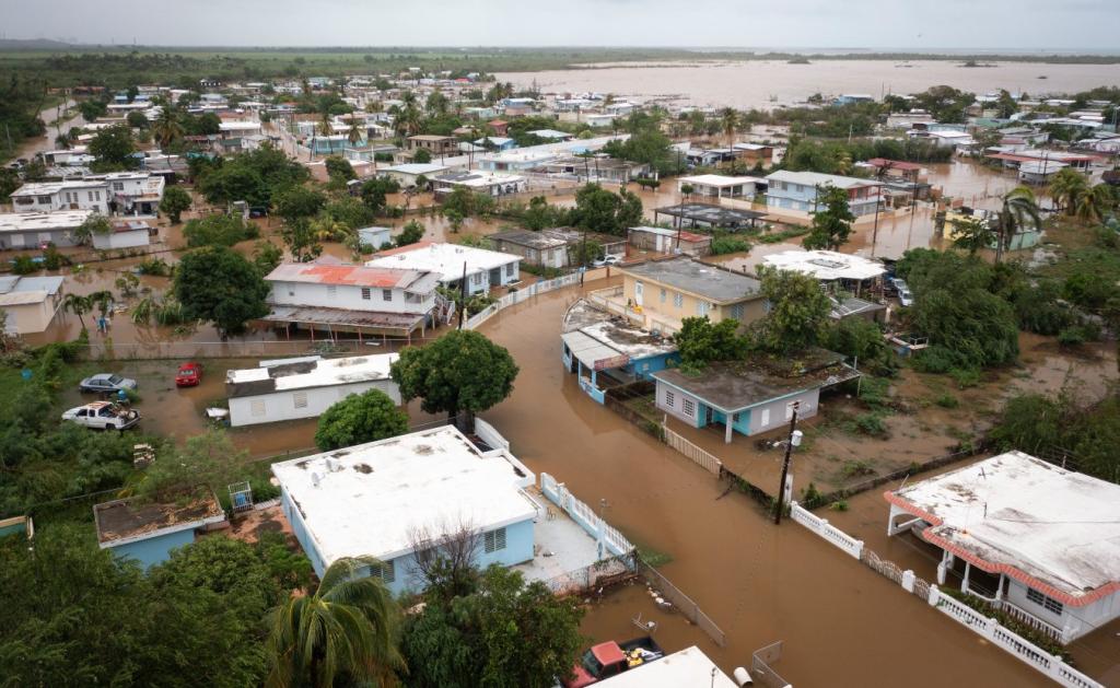 An aerial view of a street with many small homes flooded with brown water after a hurricane in Salinas, Puerto Rico, 2022