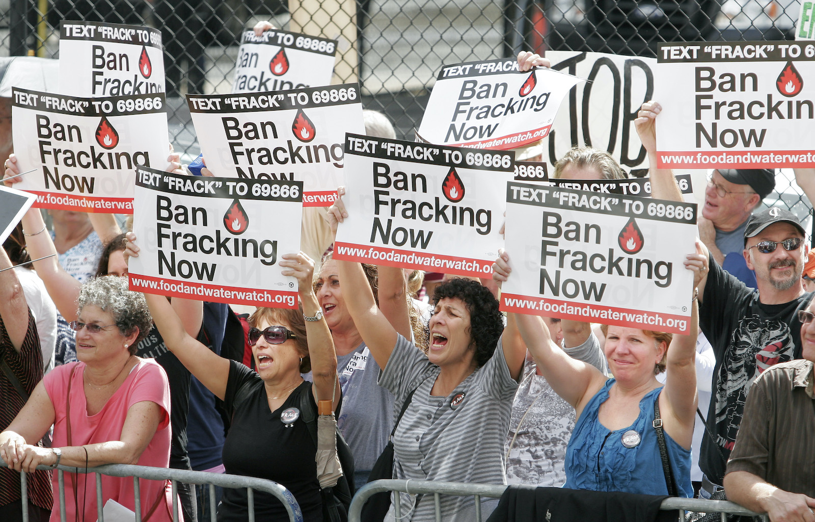 a group of protesters hold signs that say ban fracking now