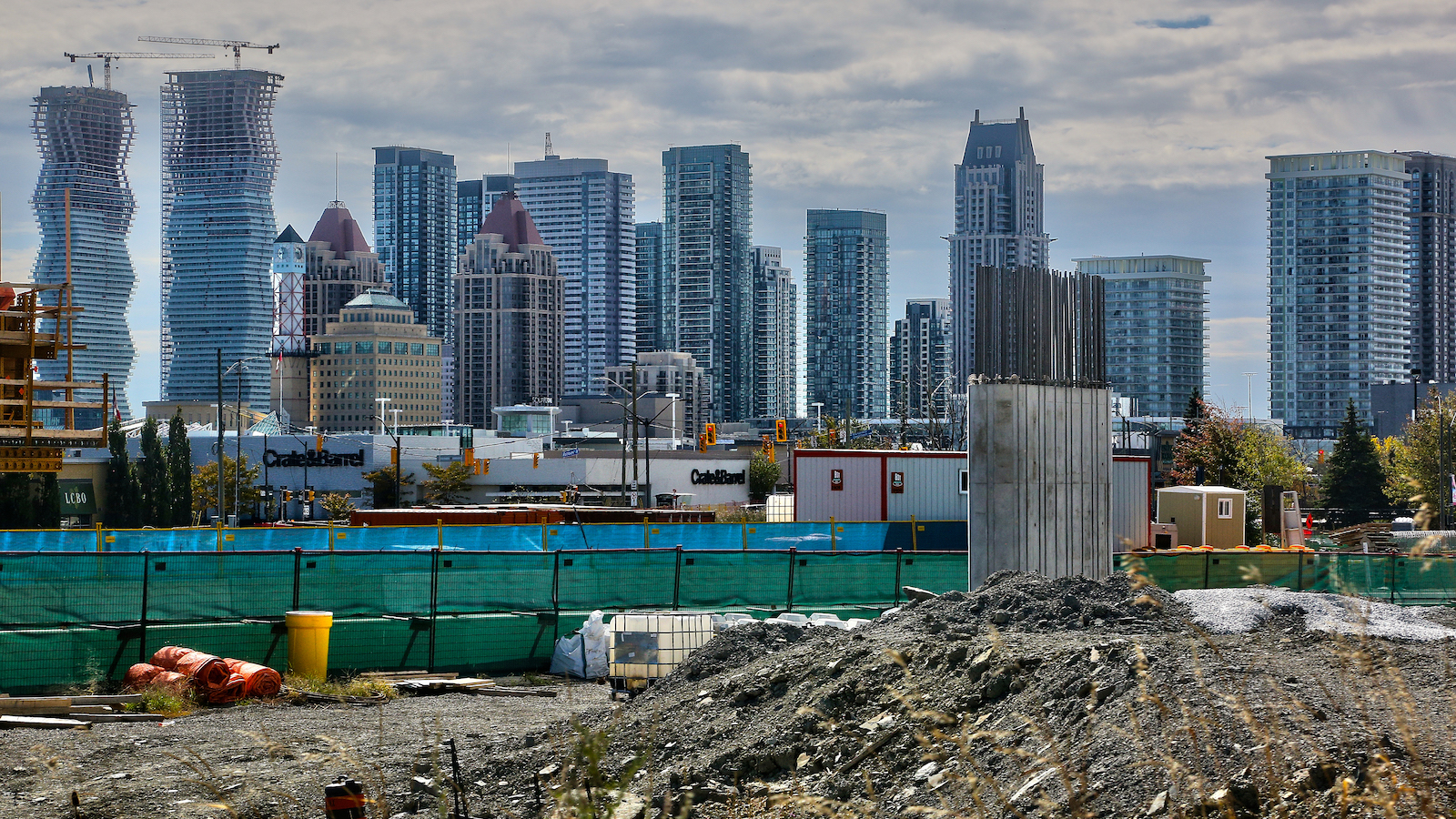 Skyline of glass, newly-constructed buildings in downtown Mississauga, Ontario with a construction site in the foreground.