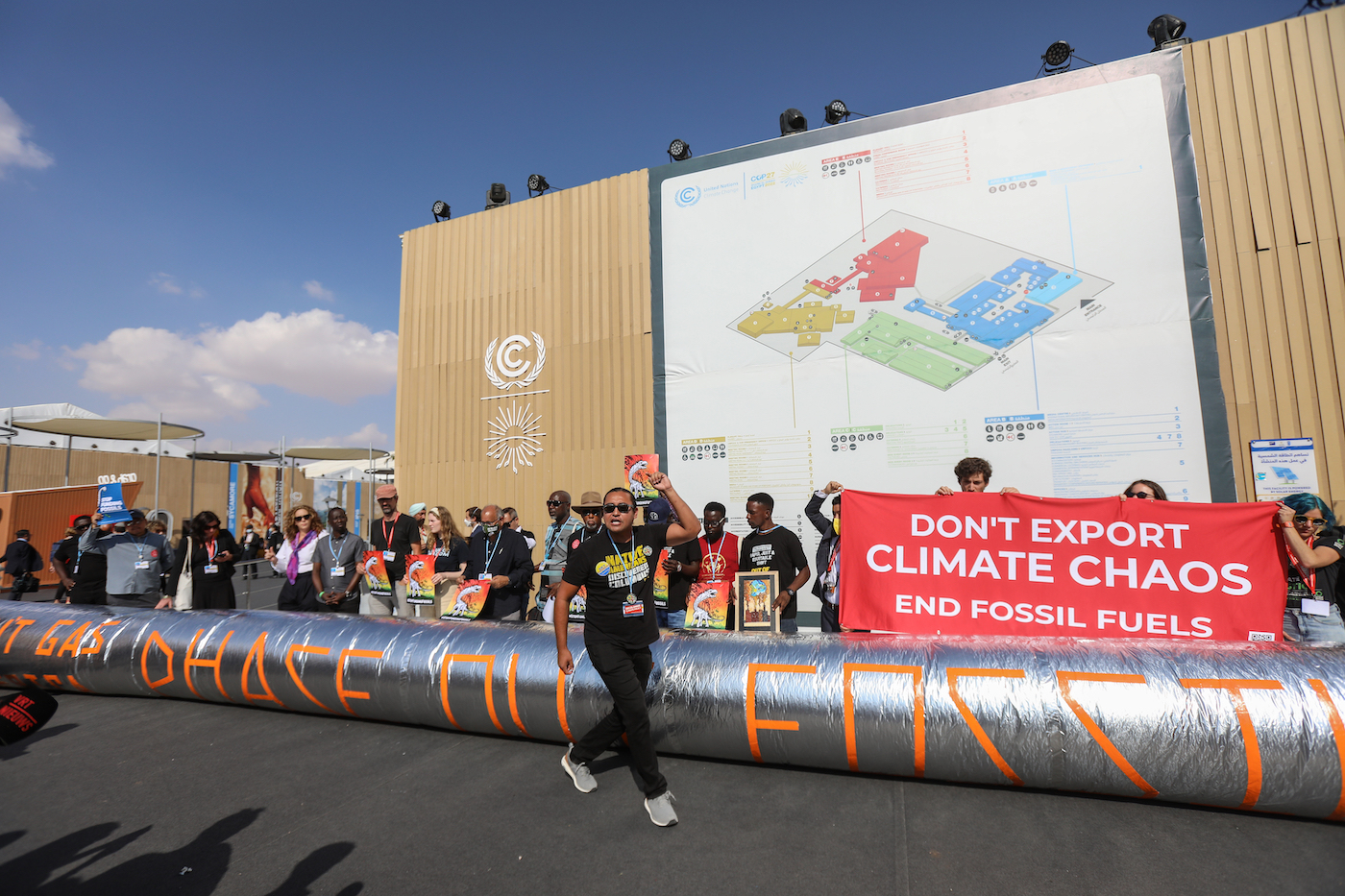 Protesters at COP27 with a prop pipeline that says phase out fossil fuels