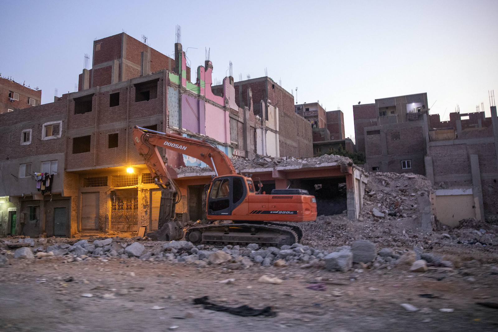 a bulldozer moves rubble from a housing site in a city