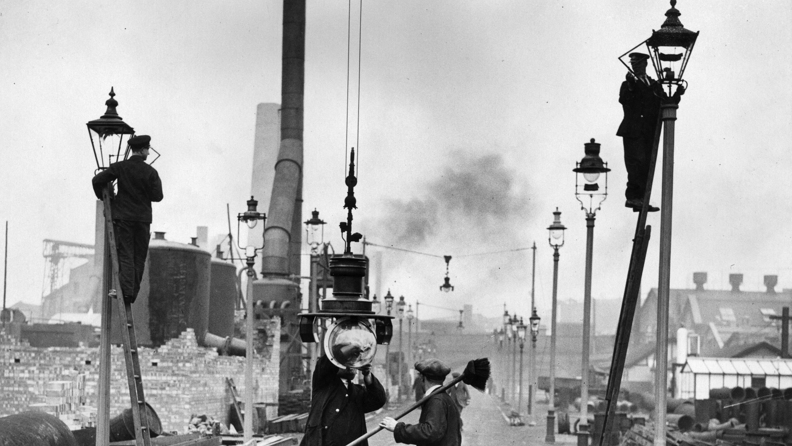 Black and white photo of construction on a London street lined with old-timey gas lamps.