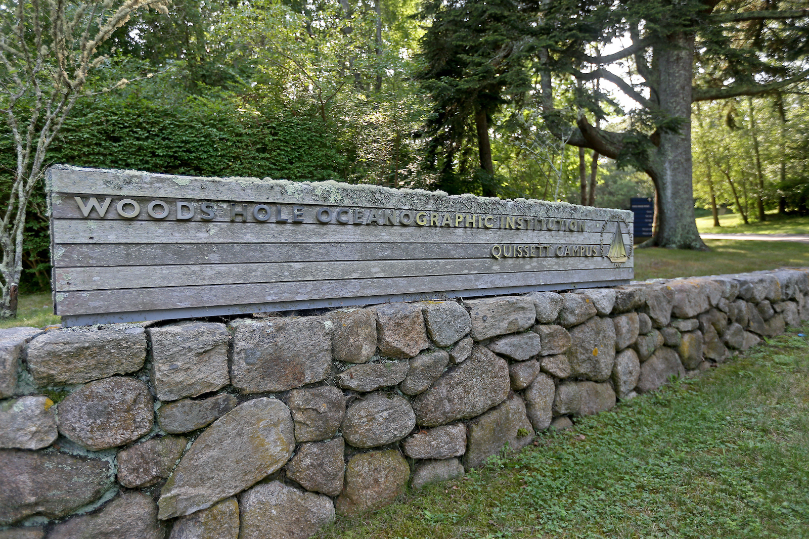 a large wooden sign stands on a stone wall