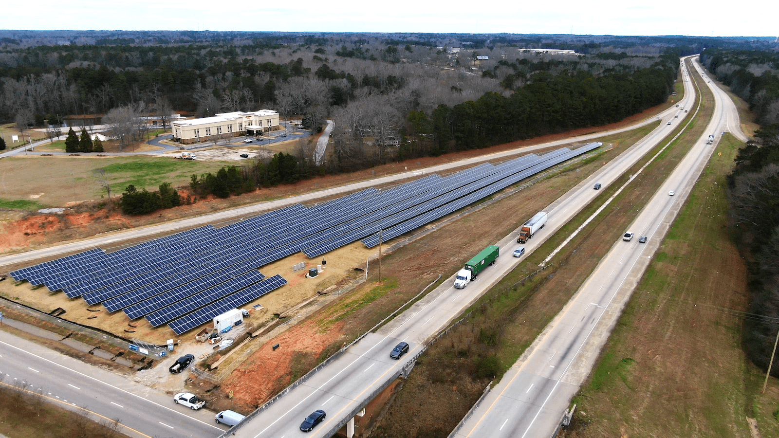 a road splits into two sections. In between in the grassy area a large many-rowed array of solar panels