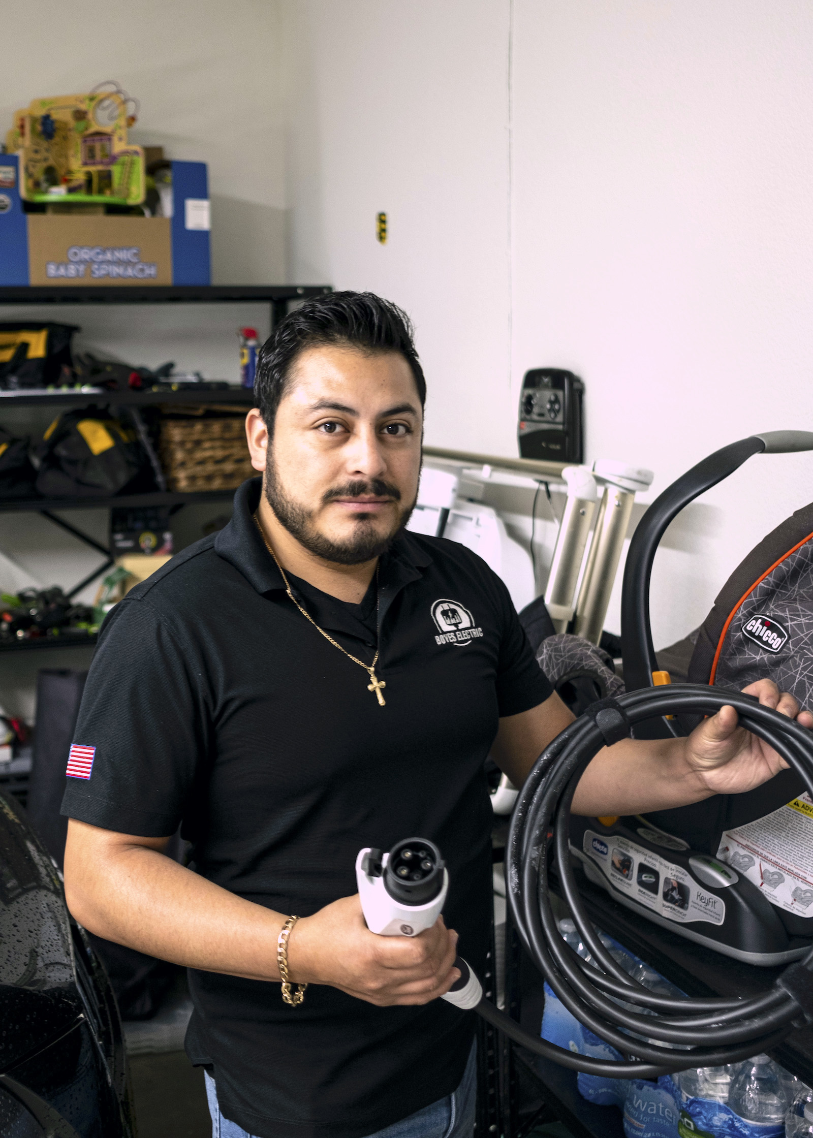 a man in a black shirt holds a car charger in a garage