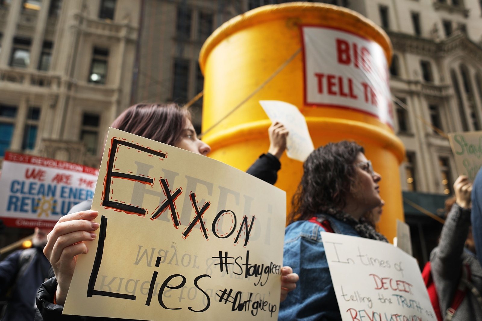 Photo of a protester holding a sign that says Exxon Lies.