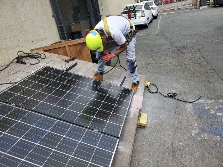 a person in a yellow hard hat works on a solar panel at a warehouse training event