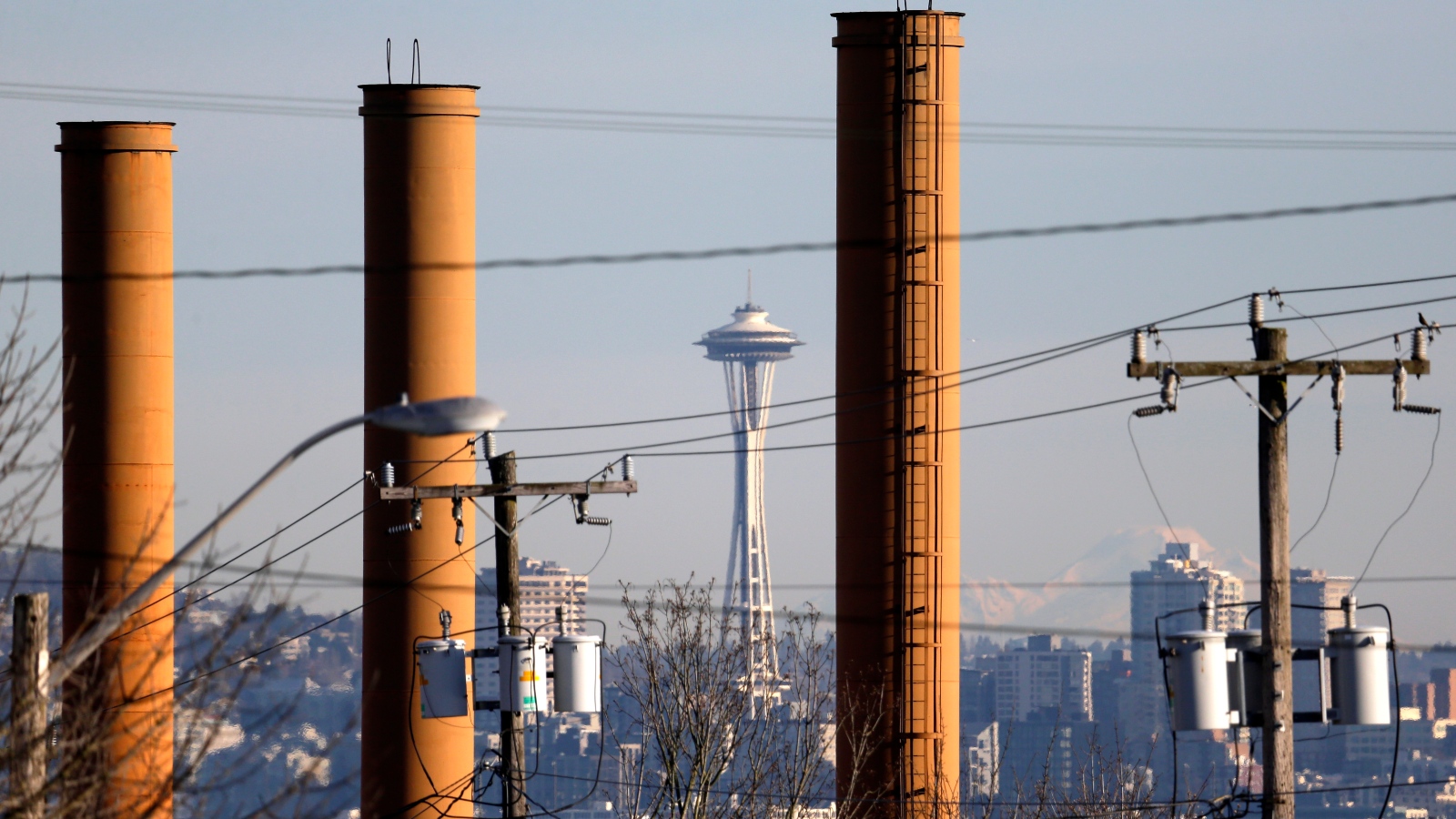 Photo of the Space Needle and downtown Seattle seen through industrial smokestacks.