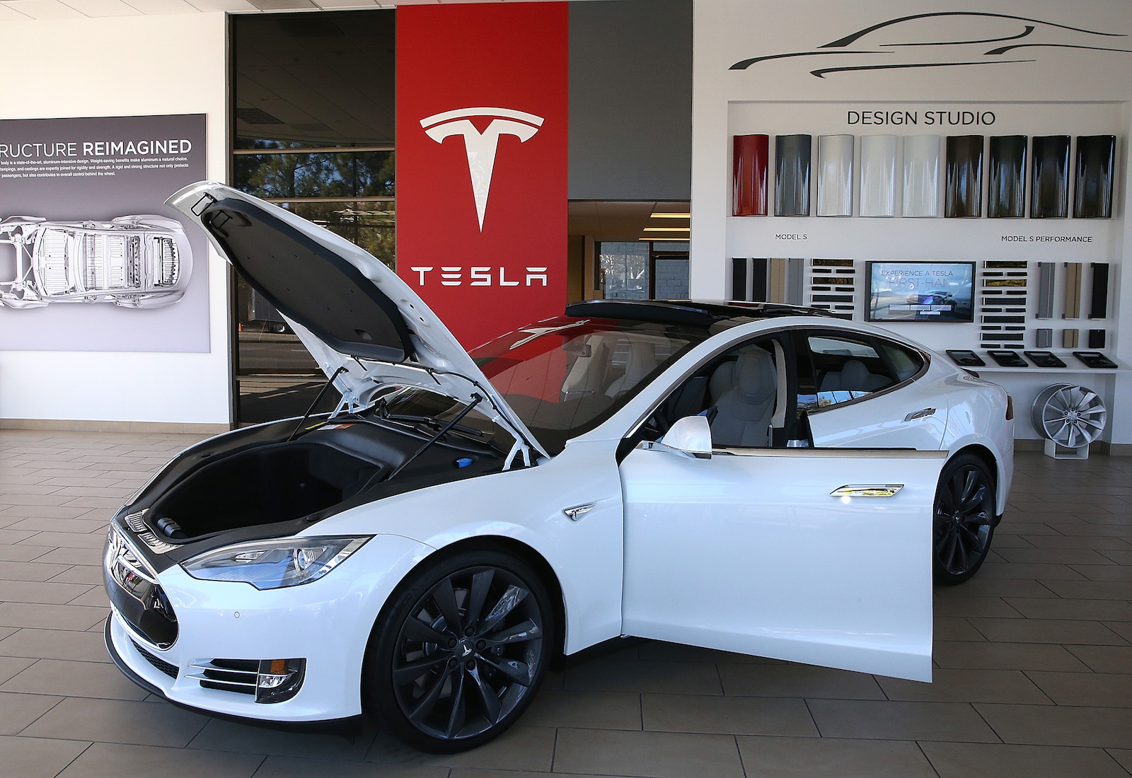 A white Tesla with the hood and doors open