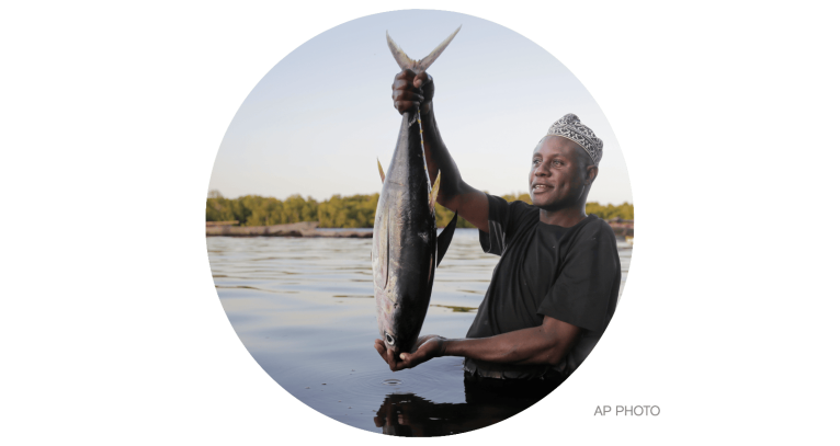 Fisherman Kassim Abdalla Zingizi holds a yellowfin tuna after a catch in Vanga, Kenya