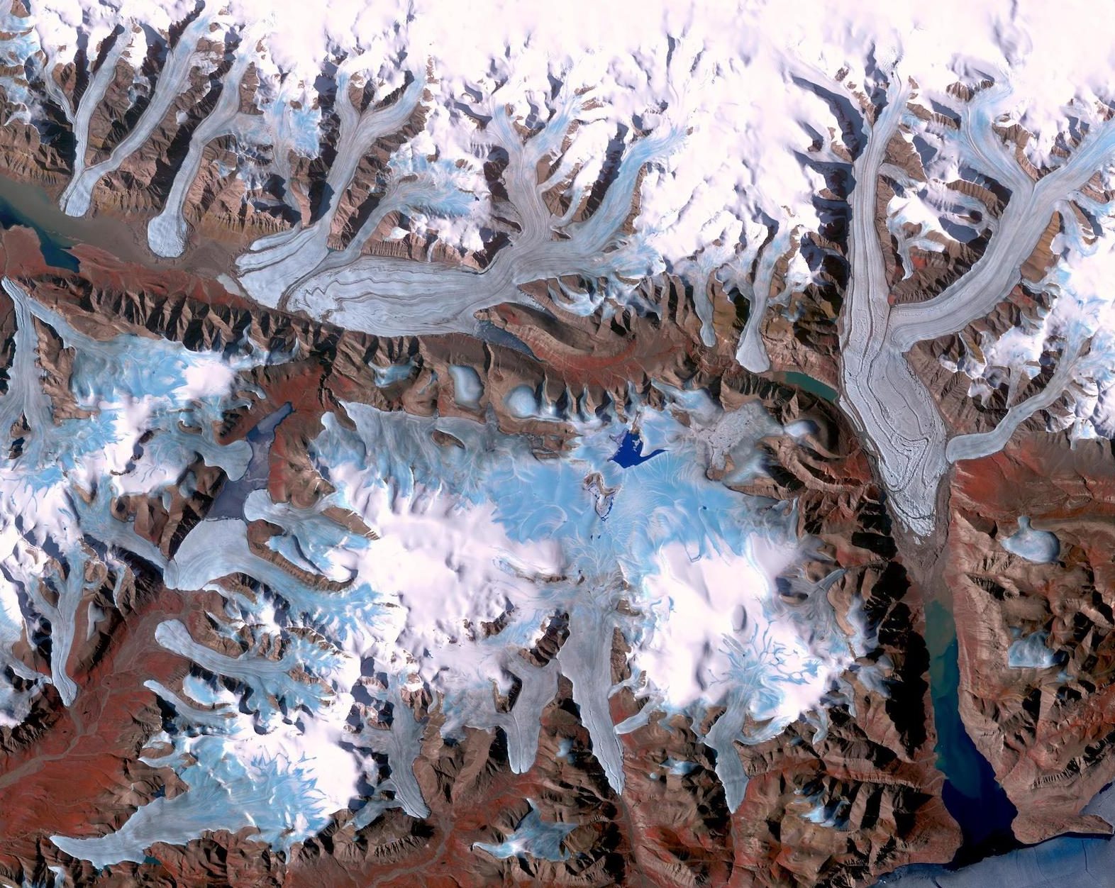 an aerial view of mountains with blue and white ice