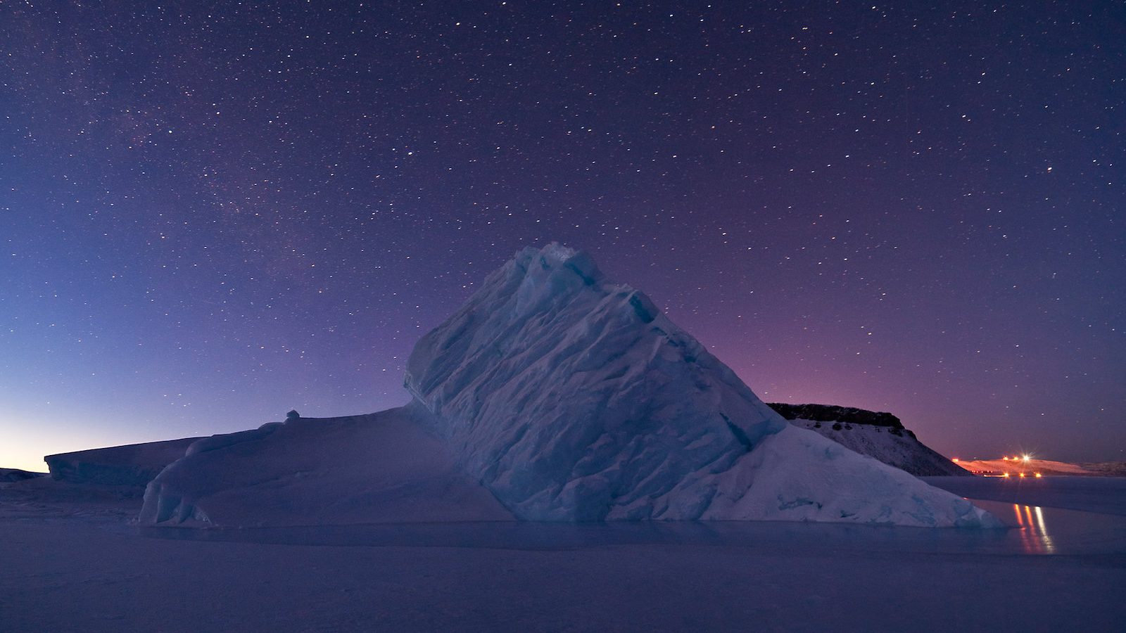 a large blue and white iceberg under dark, starry sky