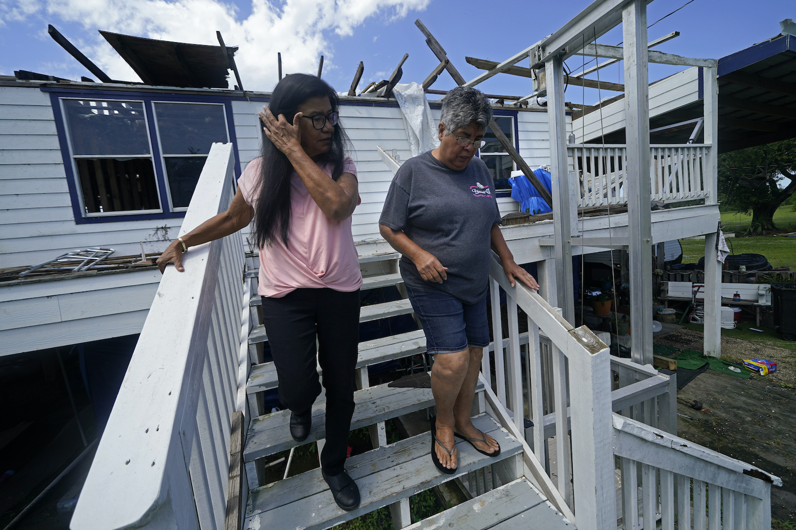 two women walk down steps connected to damaged home