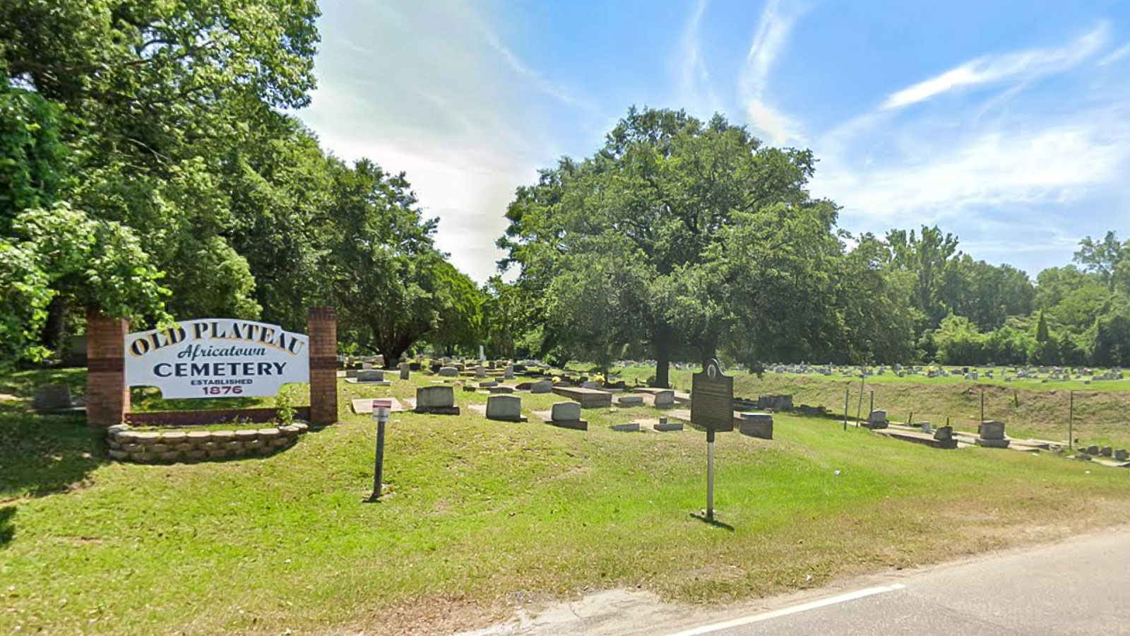 street view of Old Plateau Cemetery with sign and gravestones surrounded by trees