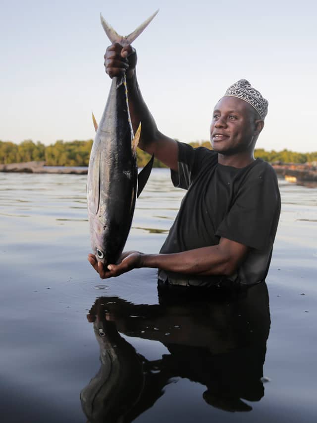 Fisherman Kassim Abdalla Zingizi holds a yellowfin tuna after a catch in Vanga, Kenya