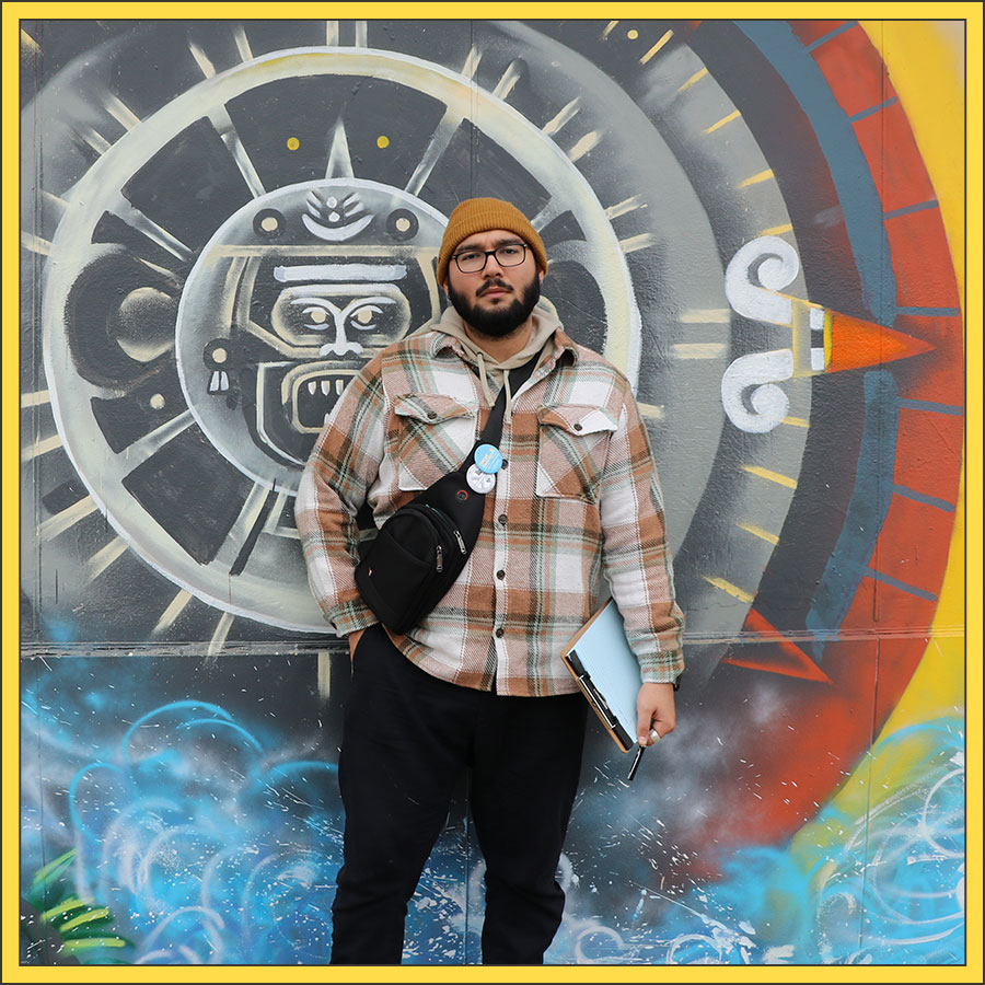 Oscar Sanchez stands in front of a mural.