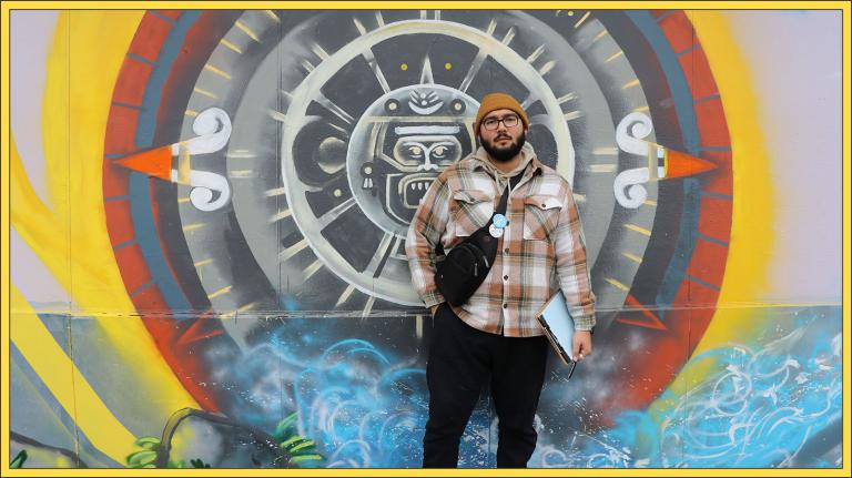 Oscar Sanchez stands in front of a mural.