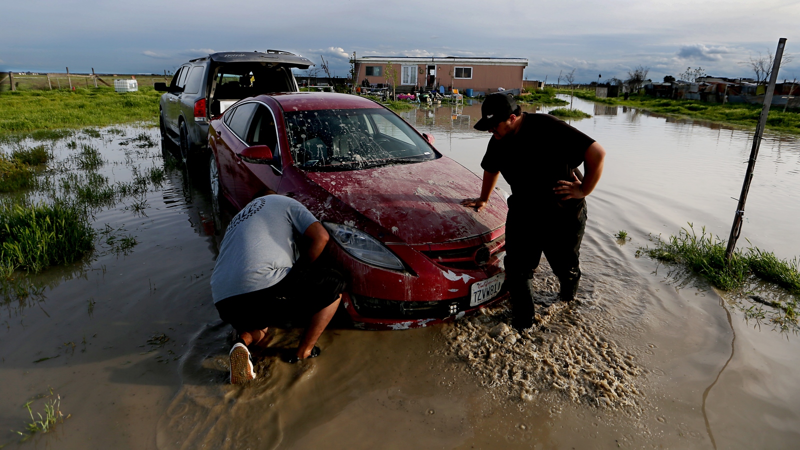 Jairo Estrada, left, and Juan Espinoza work to get one of their family's car off their flooded property in Allensworth, California. Portions of the town have flooded as Tulare Lake reappears.