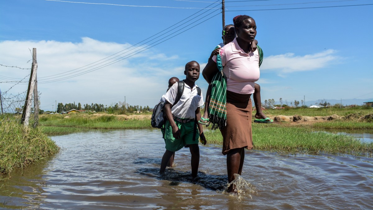 A mother and children walk on a flooded path.