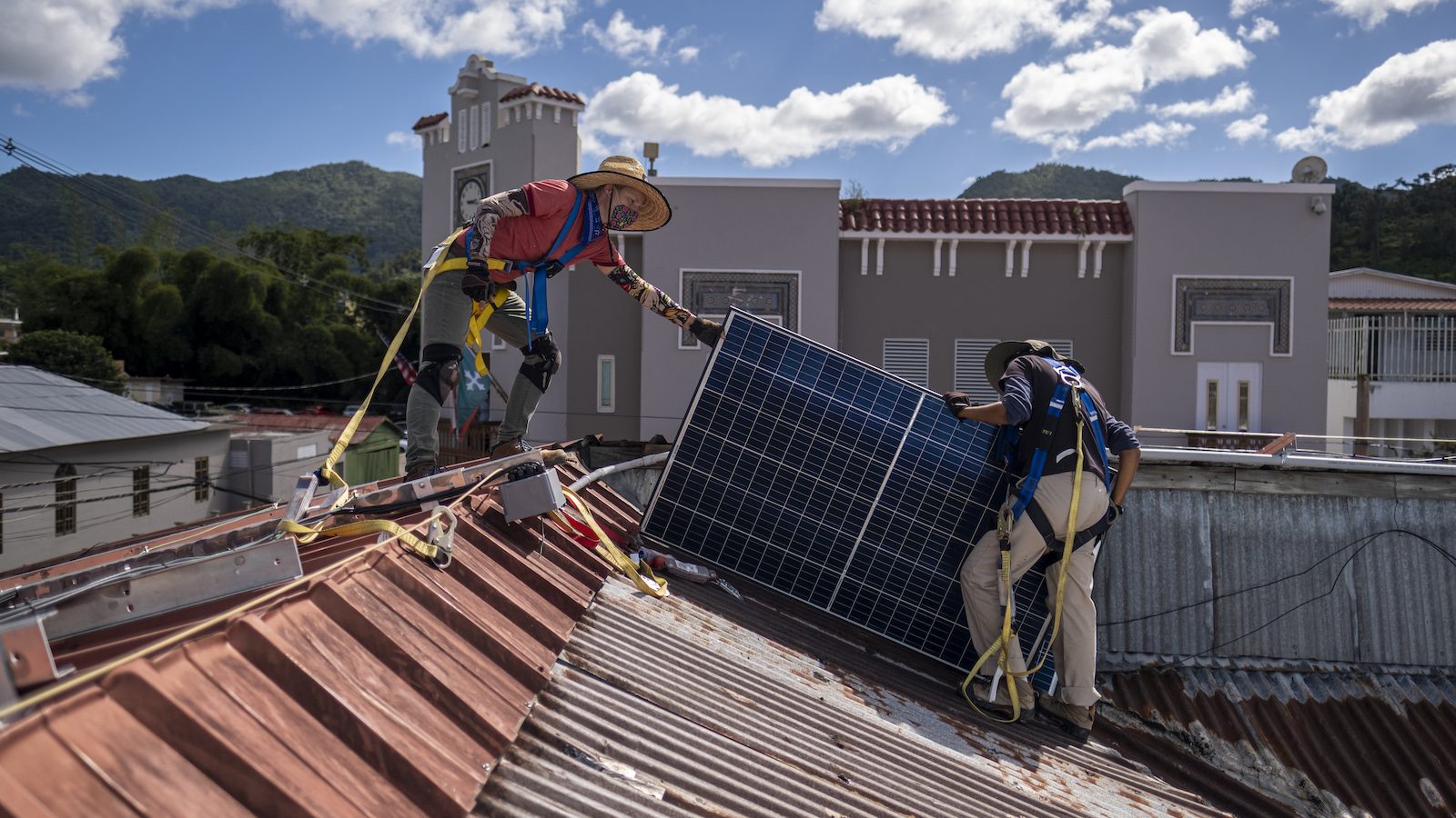Two people install rooftop solar panels