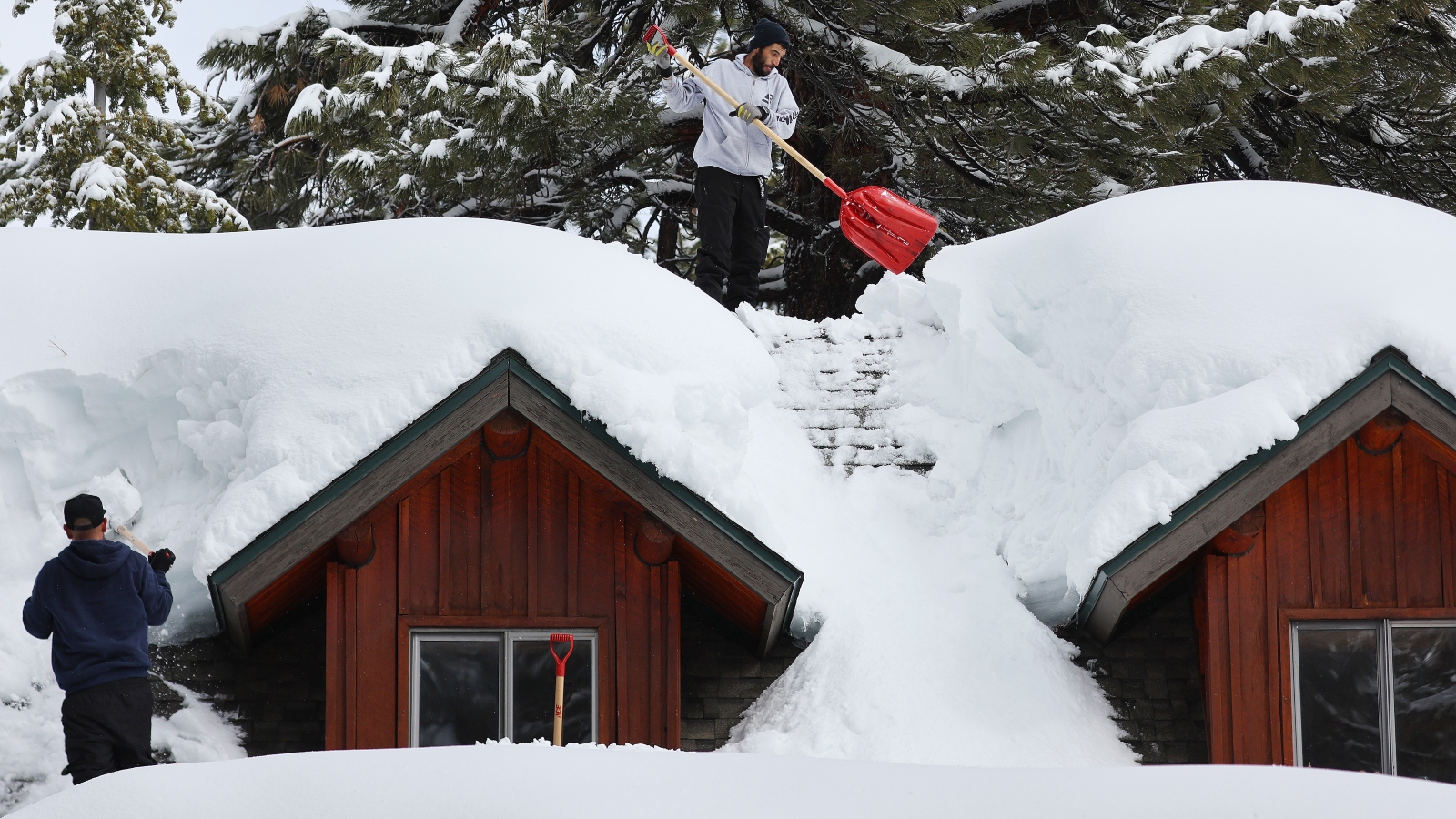 People shovel snow from a roof in Mammoth Lakes, California.