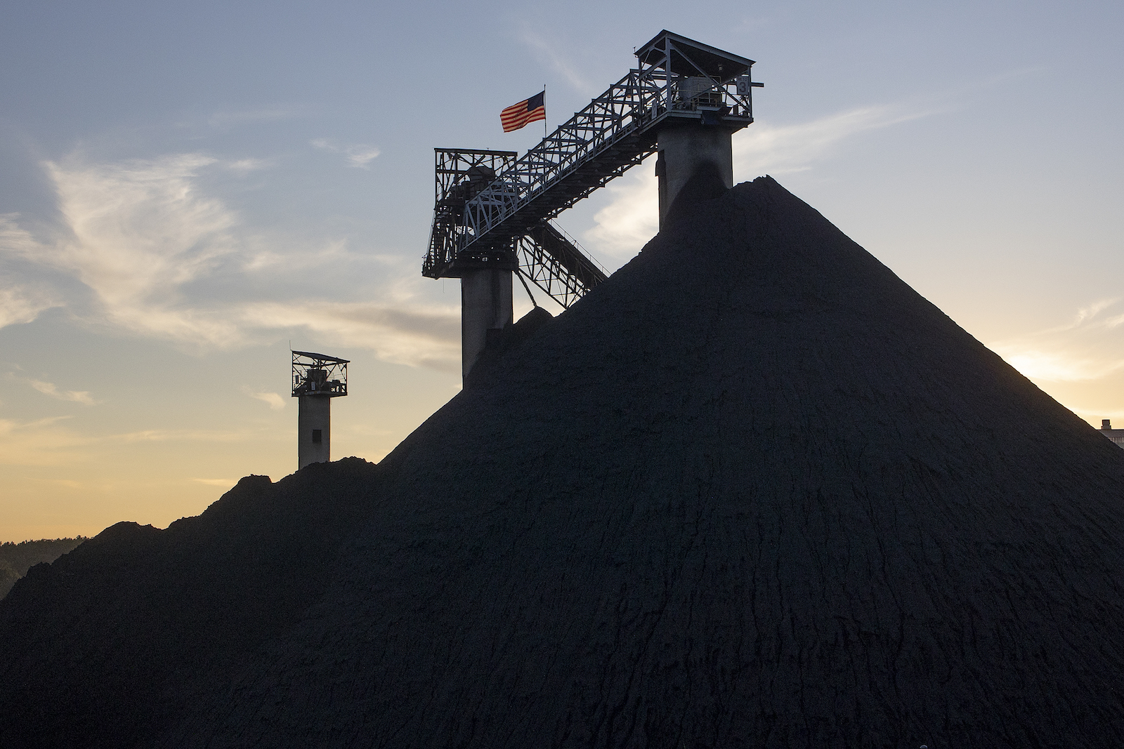 a large pile of coal near a few towers