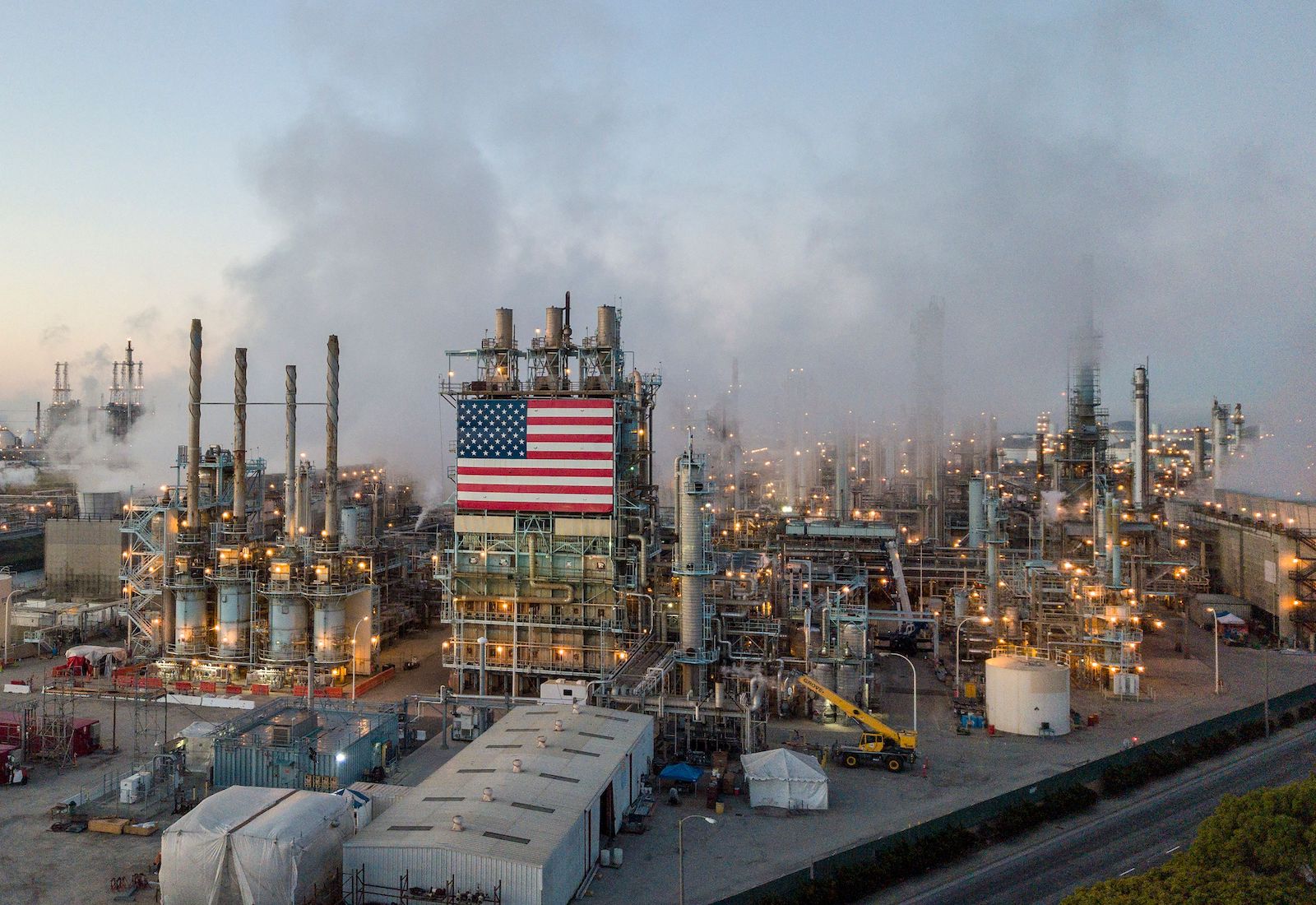 An American flag hangs from an oil refinery