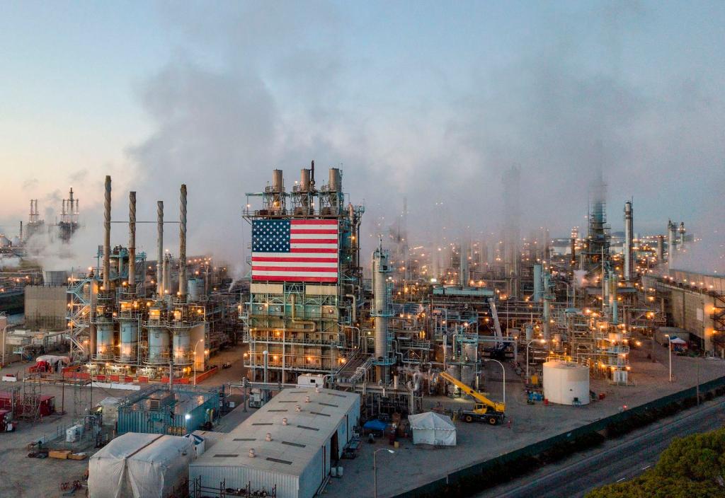 An American flag hangs from an oil refinery