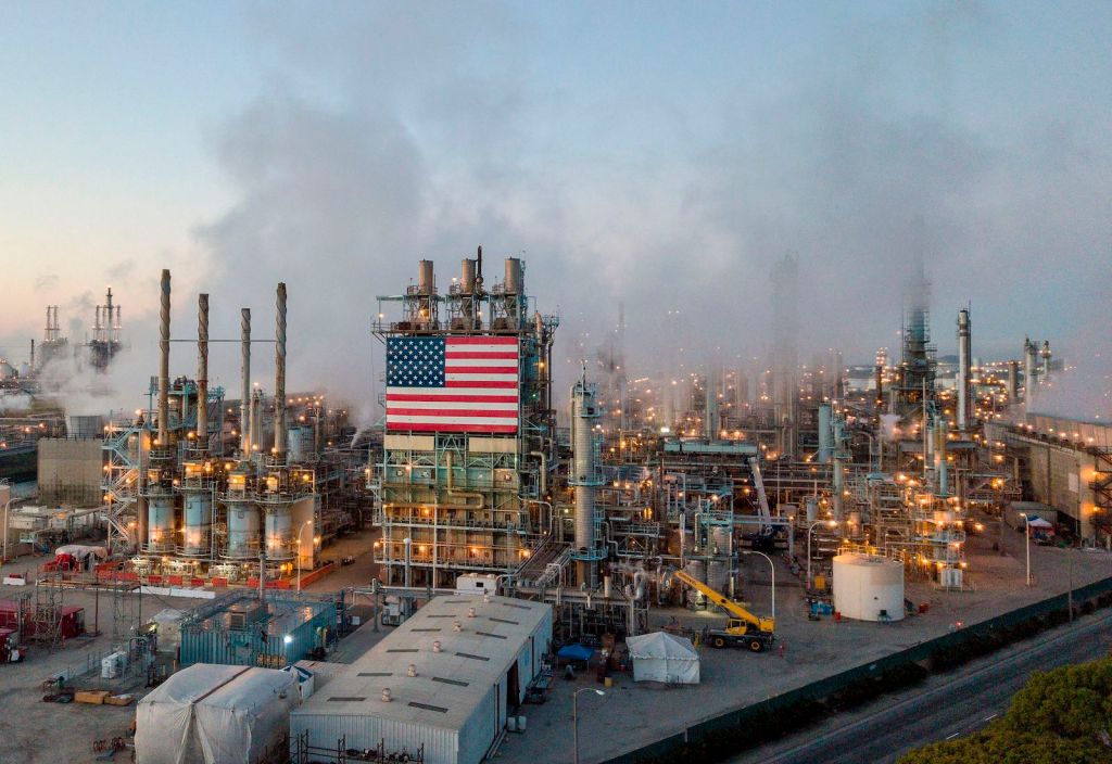An American flag hangs from an oil refinery