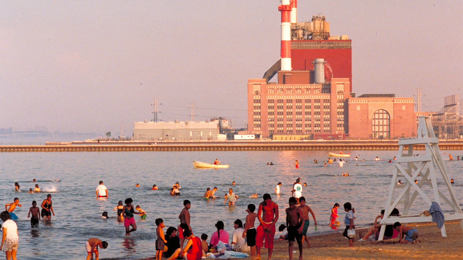 People on a beach and swimming in Lake Michigan at Calumet Park with facility in background