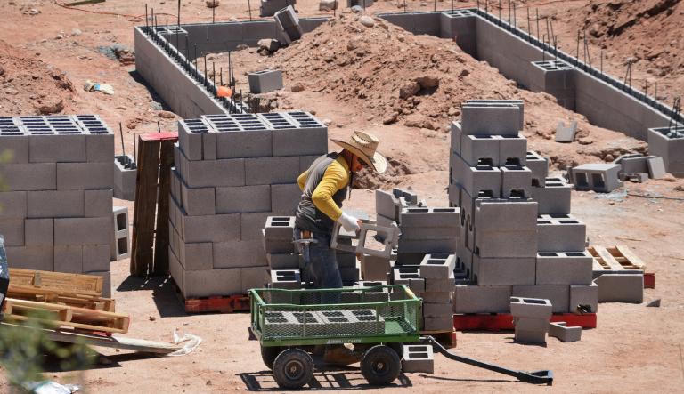 A construction worker builds the cinder block foundation for a new home