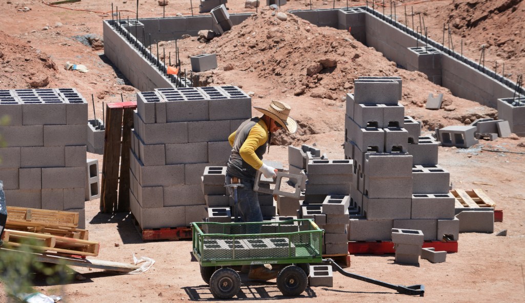 A construction worker builds the cinder block foundation for a new home