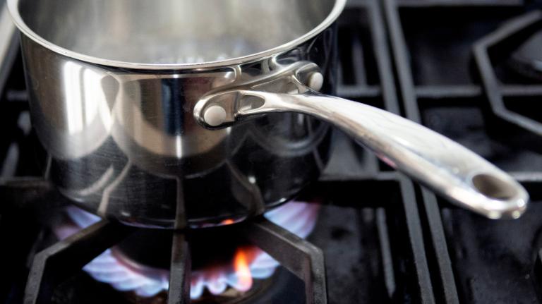Photo of a pot sitting above flames burning on a gas stove.