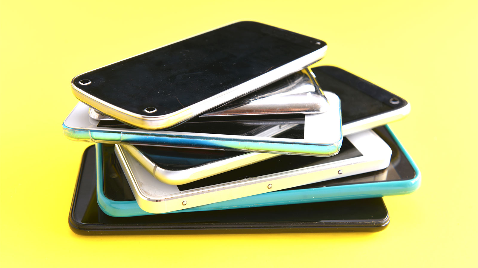 a pile of smart phones on a bright yellow background