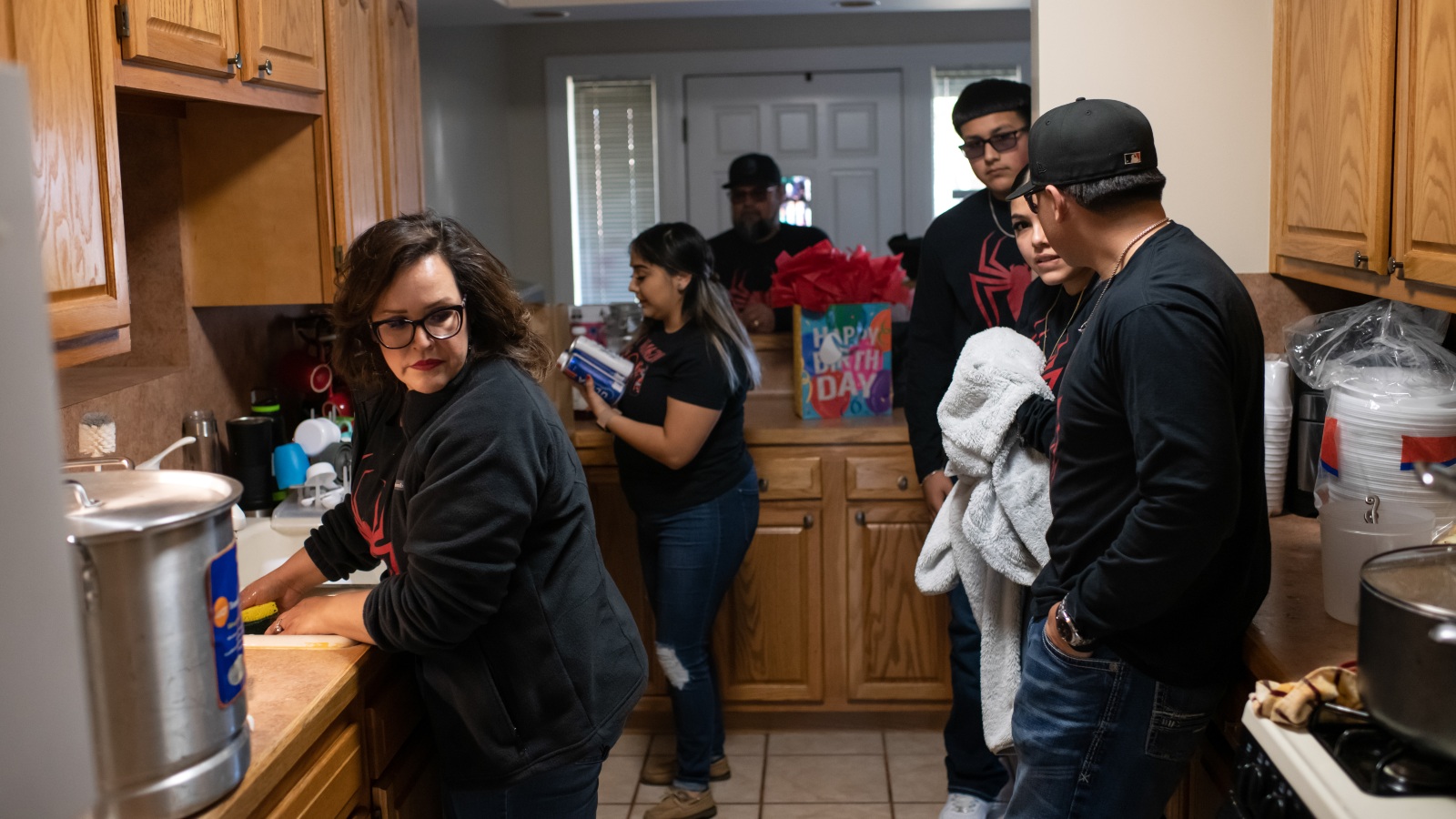 a group of people stand in a small kitchen