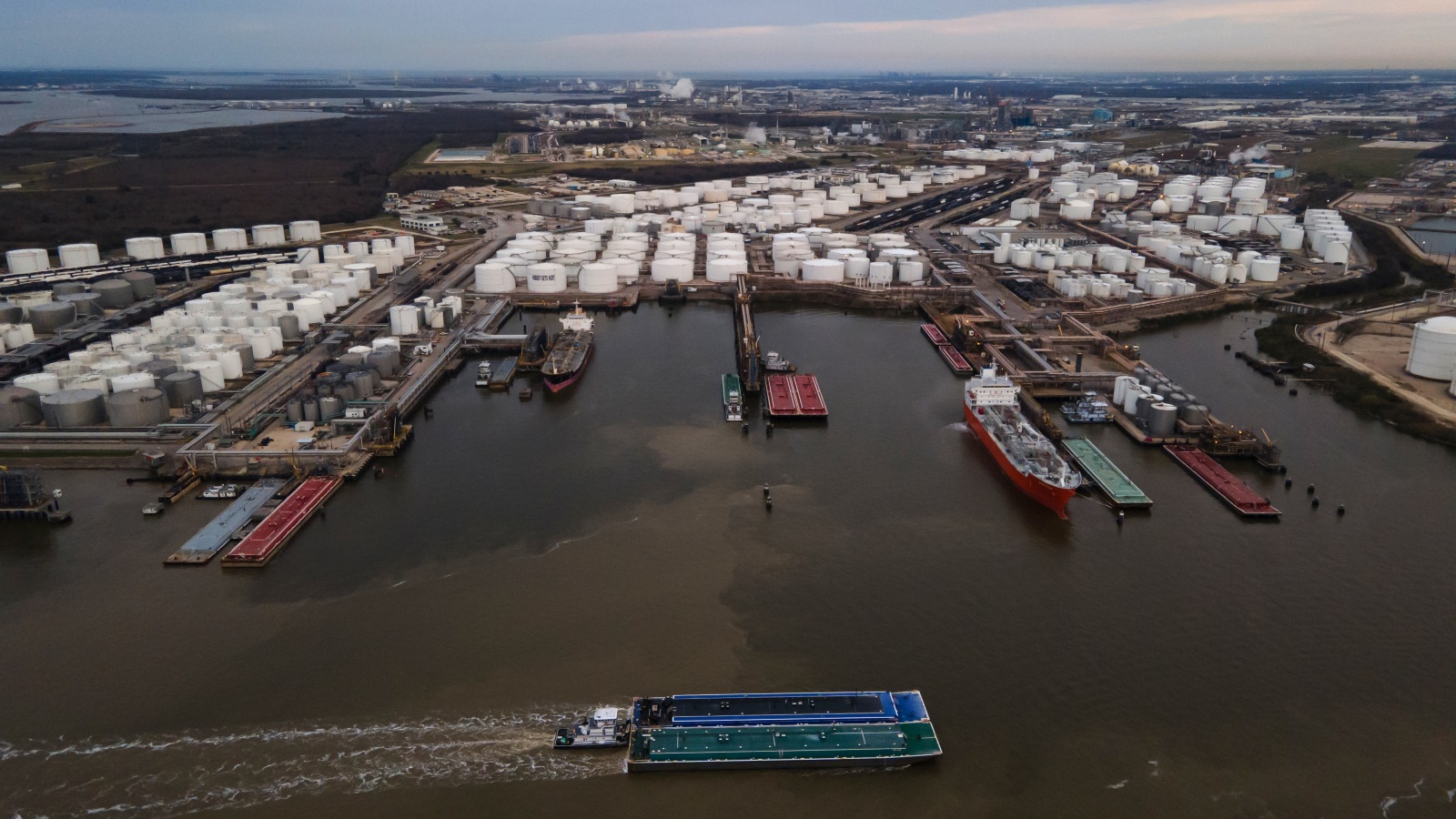 Barges float through the Houston Ship Channel’s murky waters