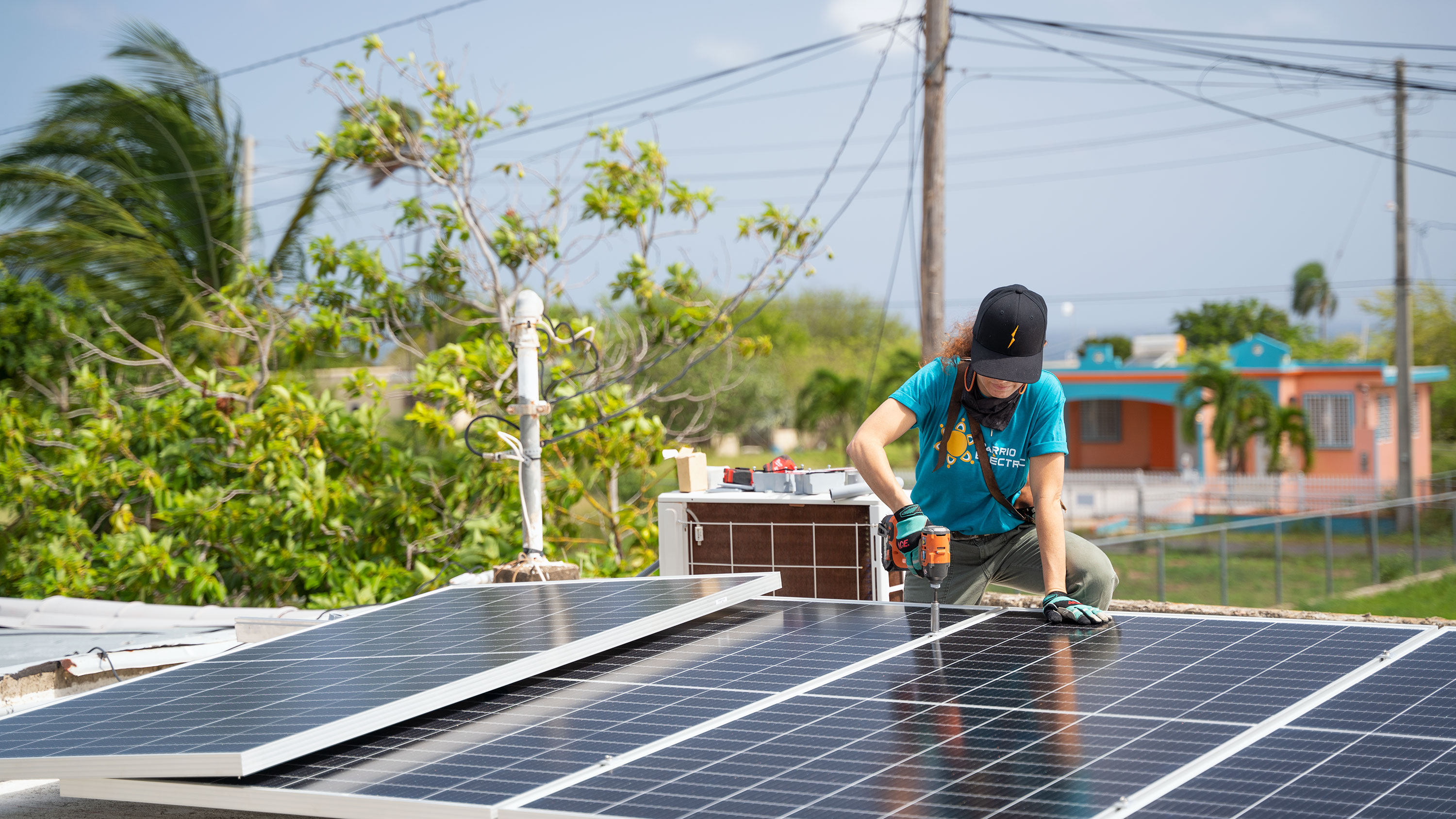 A woman installs solar panels on a roof in Isabela, Puerto Rico.