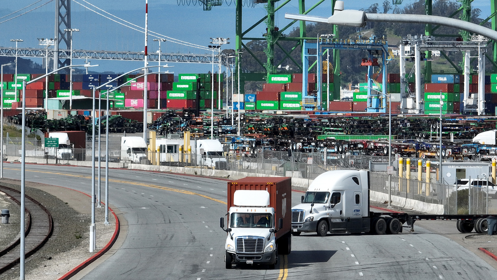 A truck turns onto a road carting a shipping container from a port.