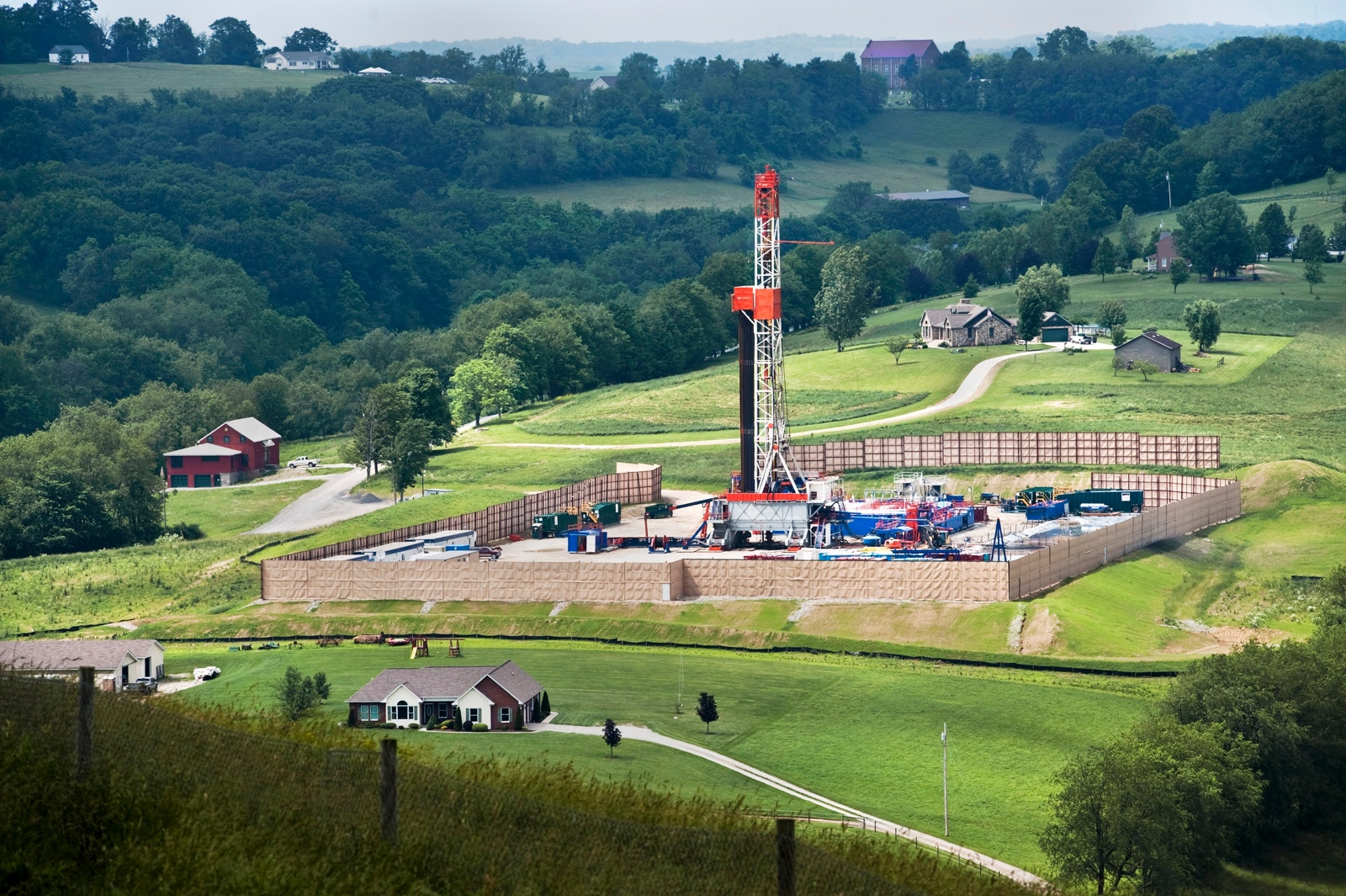 Rolling hills and forest are interrupted by an enclosure with a gas installation.