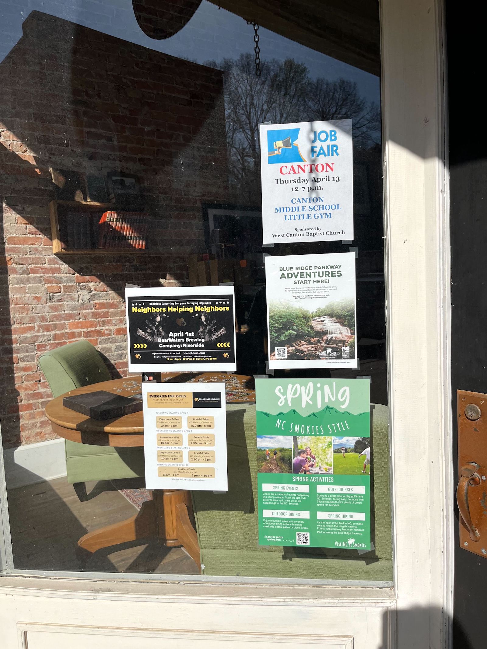 Paper flyers and posters advertising job fairs and resources to help millworkers hang in the window of a cafe in Canton, North Carolina.
