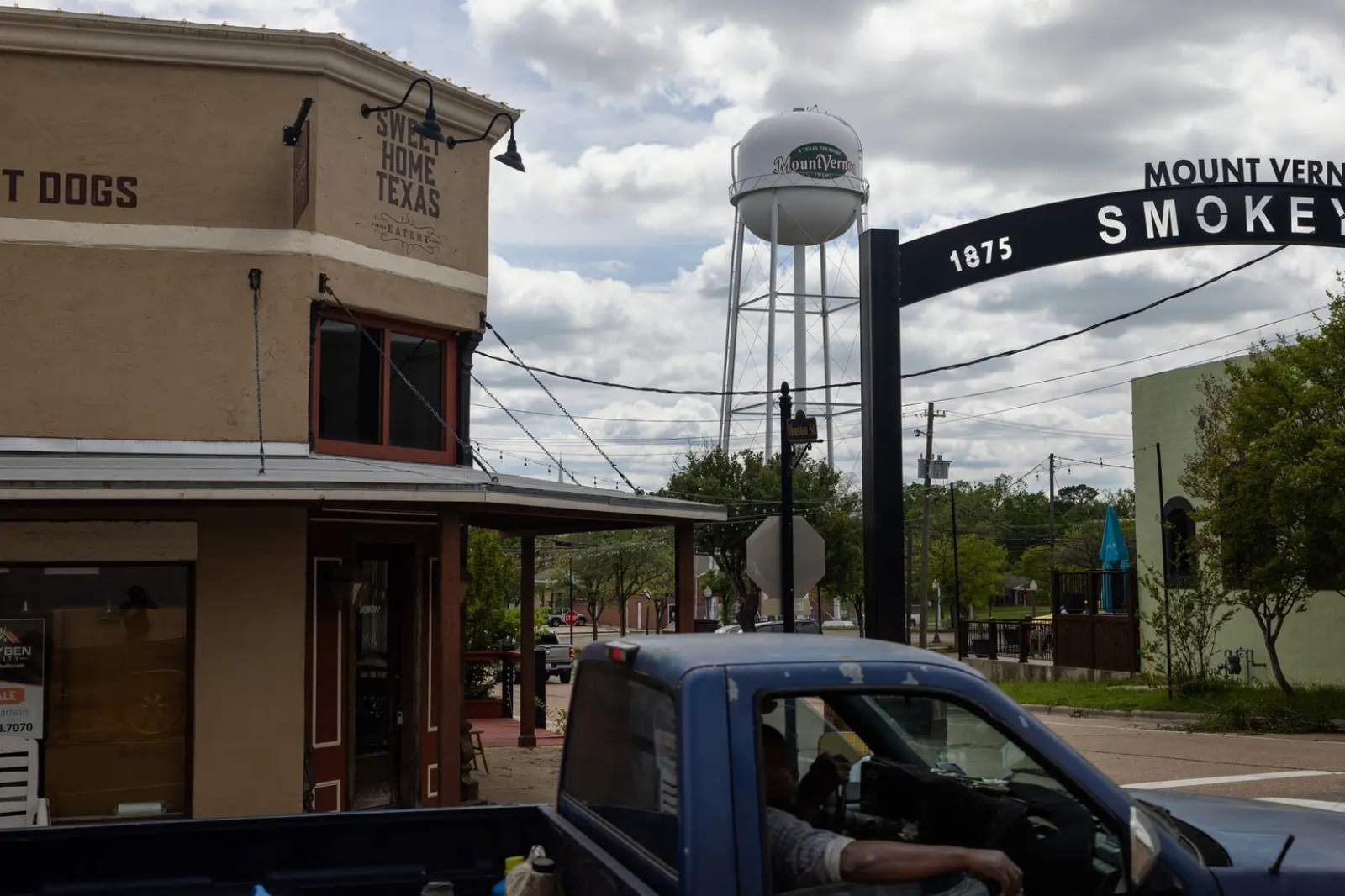 A truck drives through a small town with a water tower.