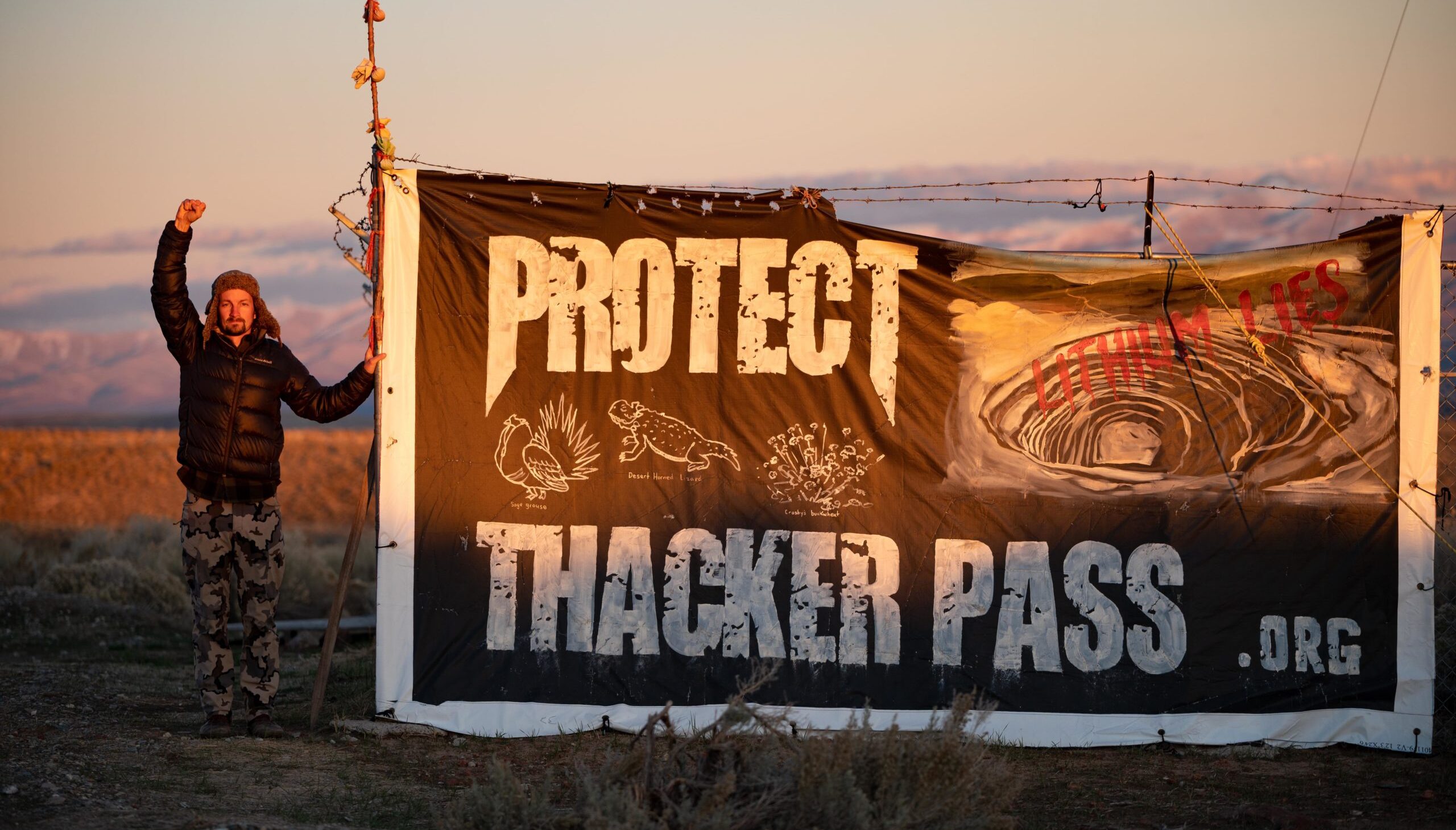 protester holding a sign that says protect thacker pass