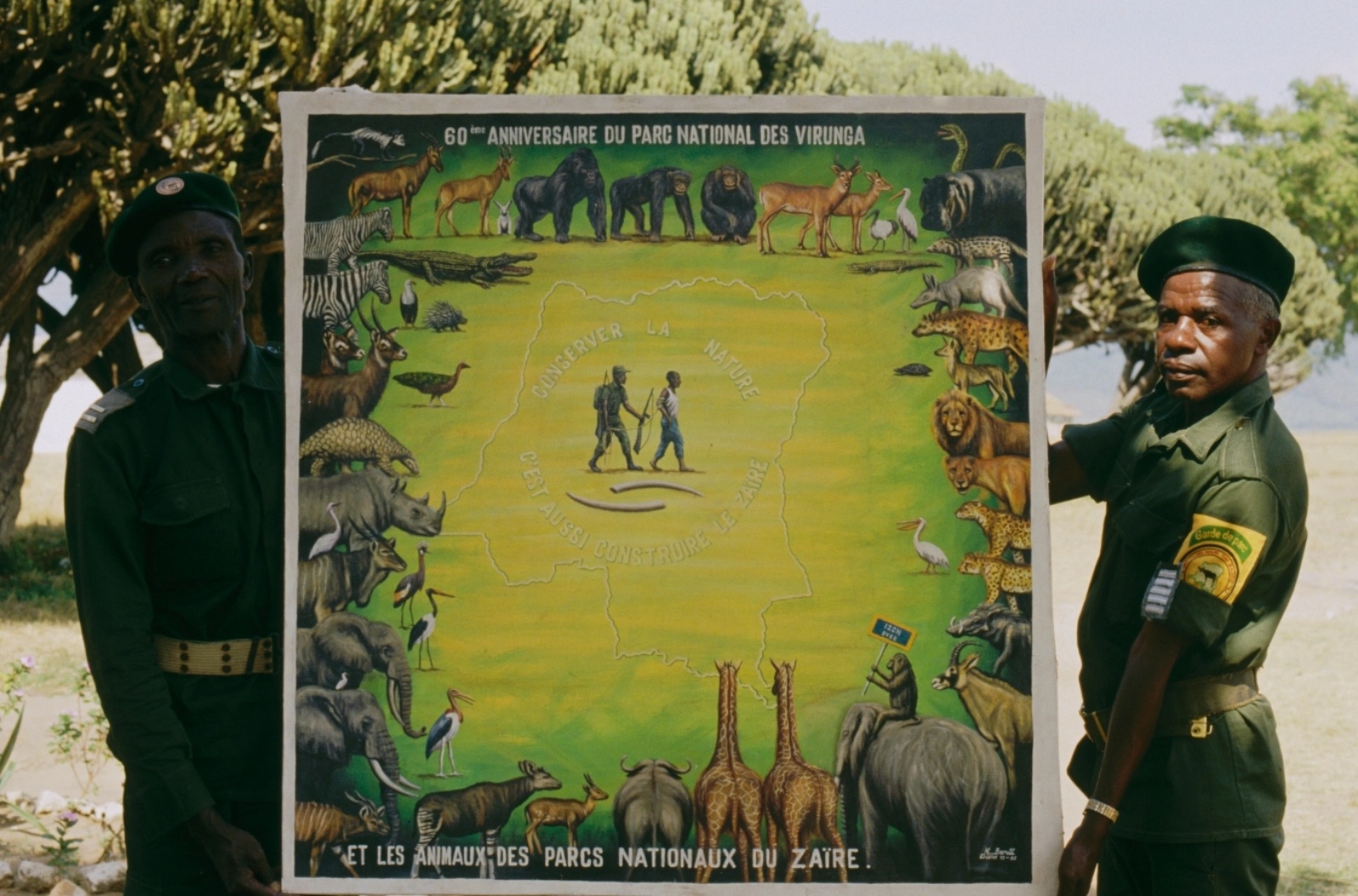 Two guards for Virunga National Park in the Democratic Republic of Congo hold up a poster commemorating the 60th anniversary of the park.