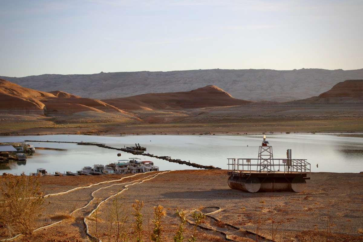A dock sits in sand, next to a shallow pool of water in the middle of the desert.