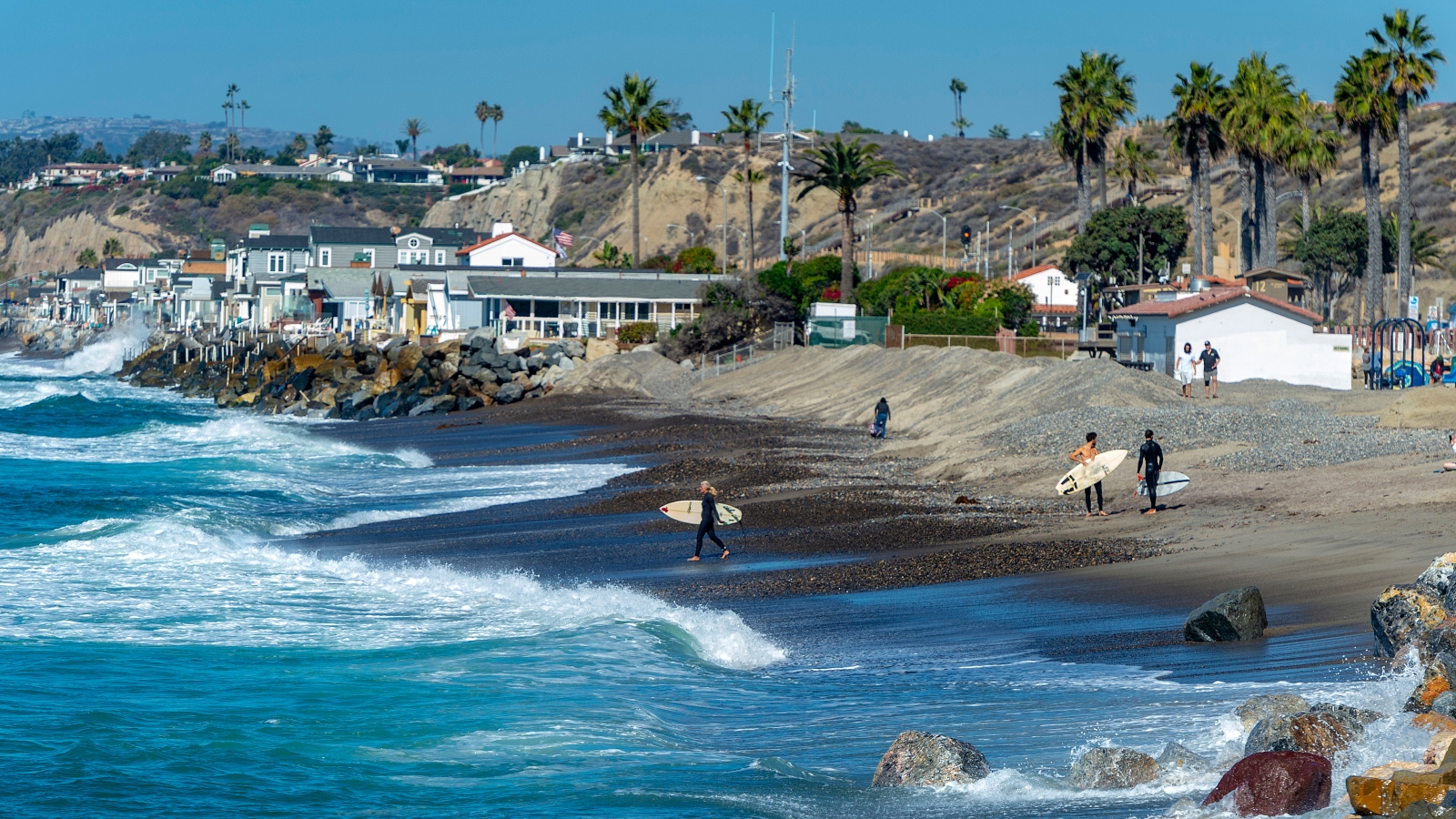 Surfers walk along a shrinking beach in San Clemente, California, south of Los Angeles.