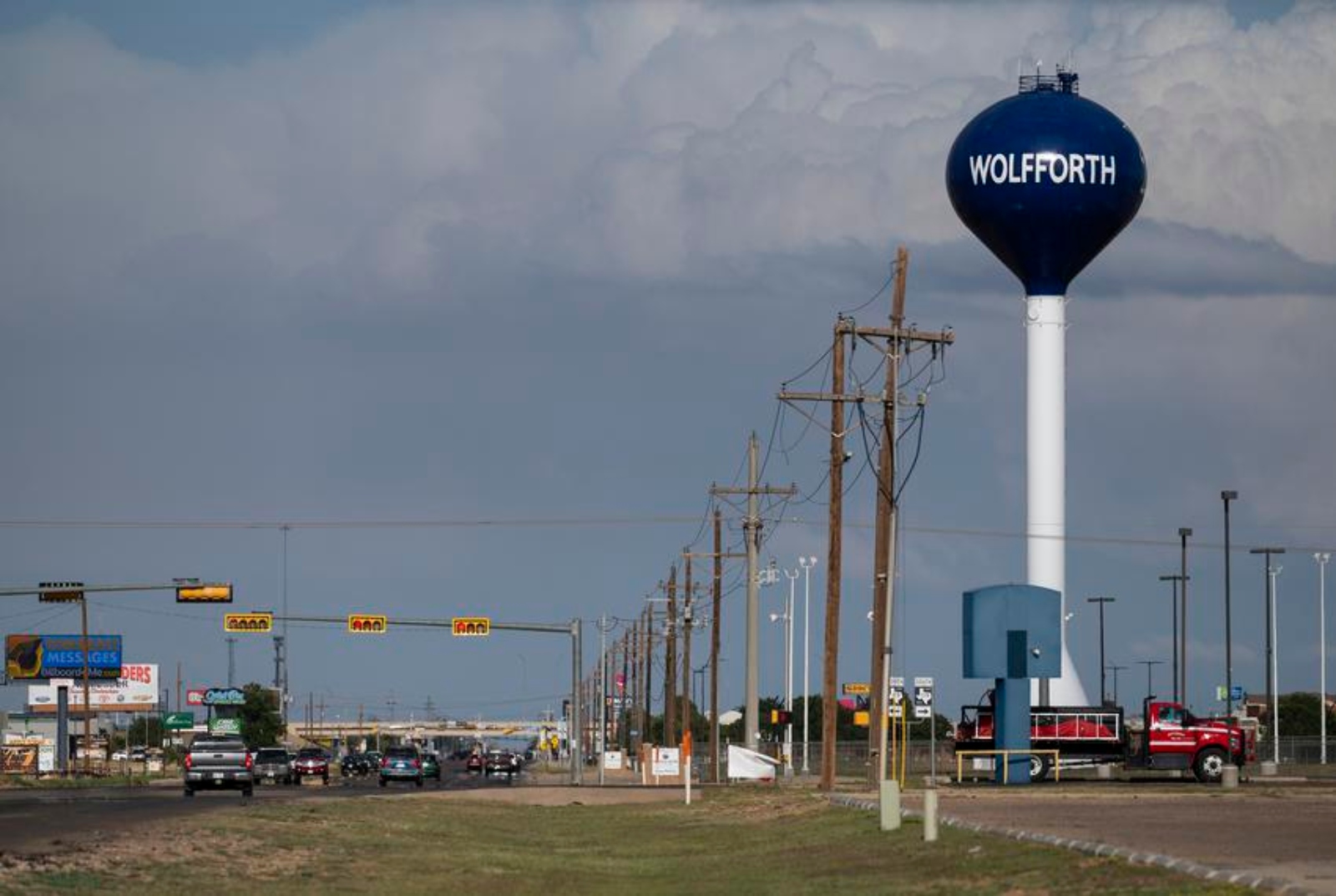 A road along a power line and a water tower that reads Wolfforth.
