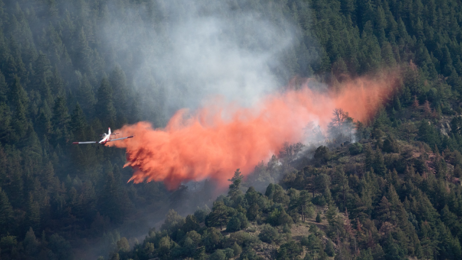 A low-flying plane drops fire retardant on a wildfire in Colorado