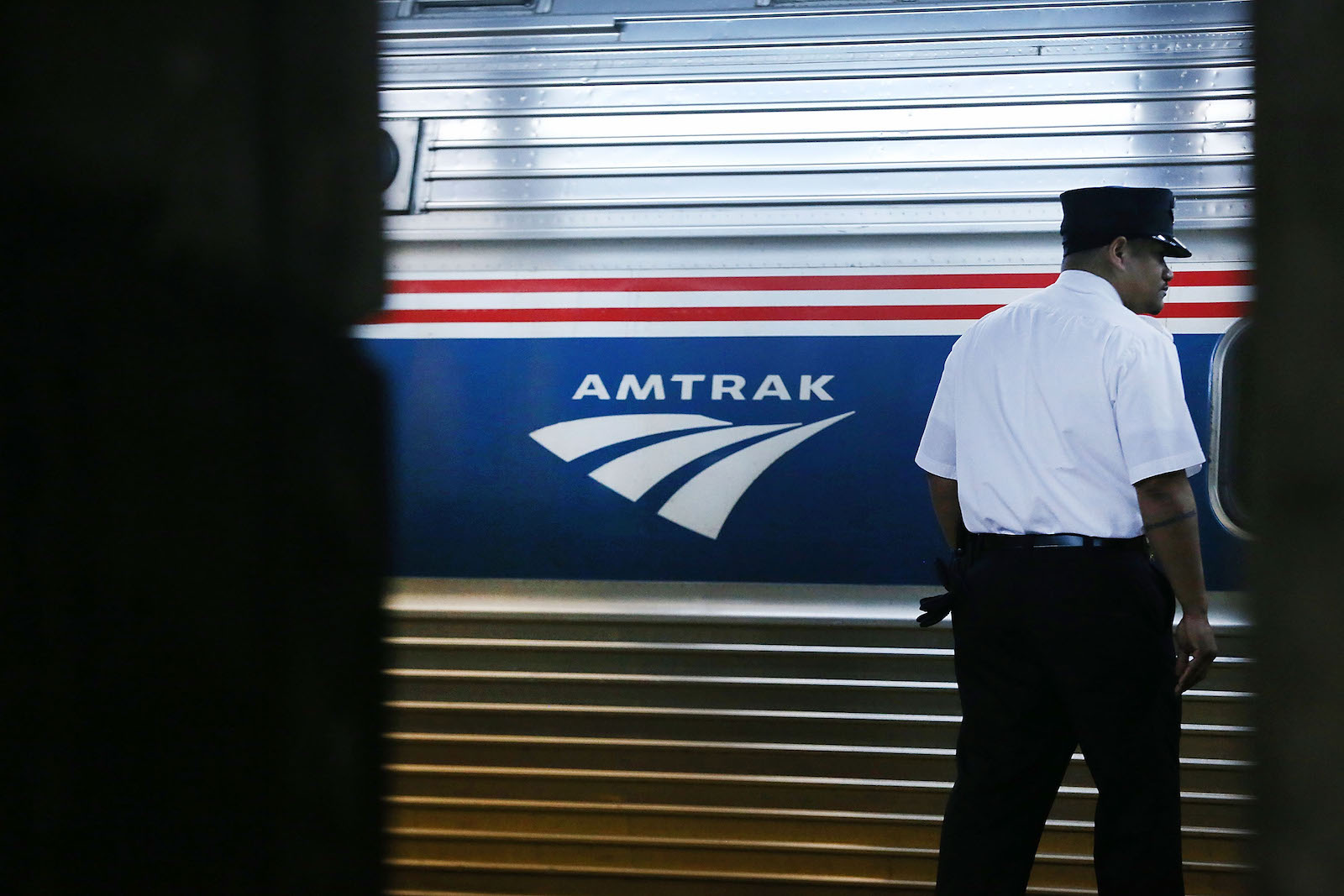 a man in a uniform stands outside an amtrak train